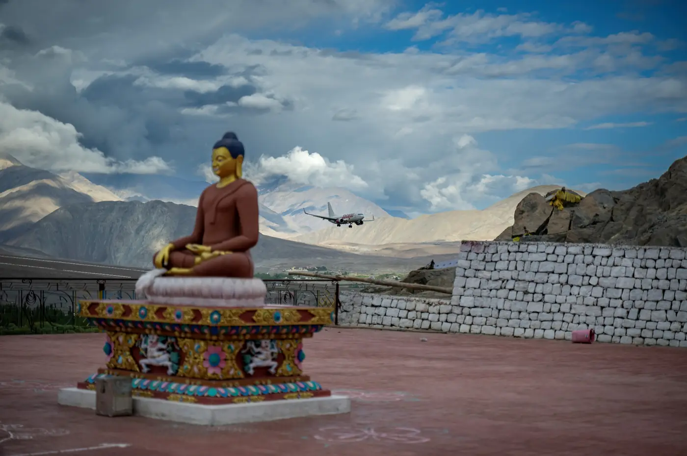 Buddha statue above Leh with an aircraft on approach